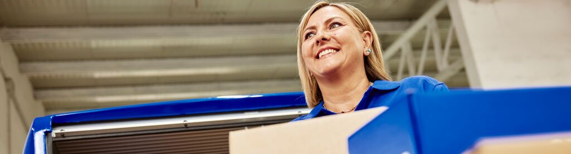 GLS driver smiling while holding a parcel in front of an open delivery van
